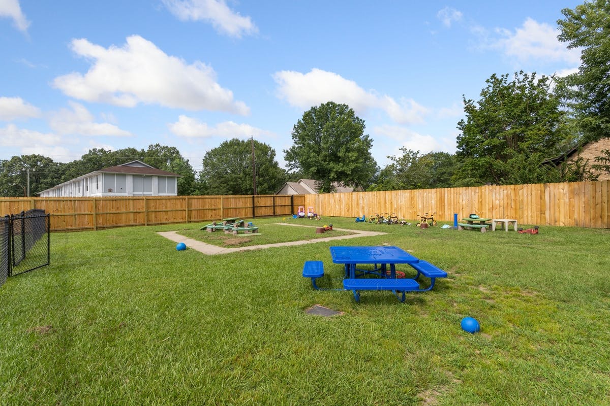 Outdoor play area with a blue picnic table, tricycles, and sandboxes