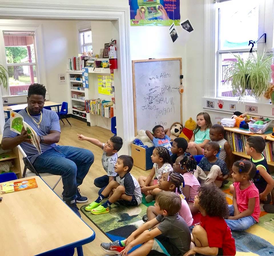Person reading a book to a group of children in a classroom