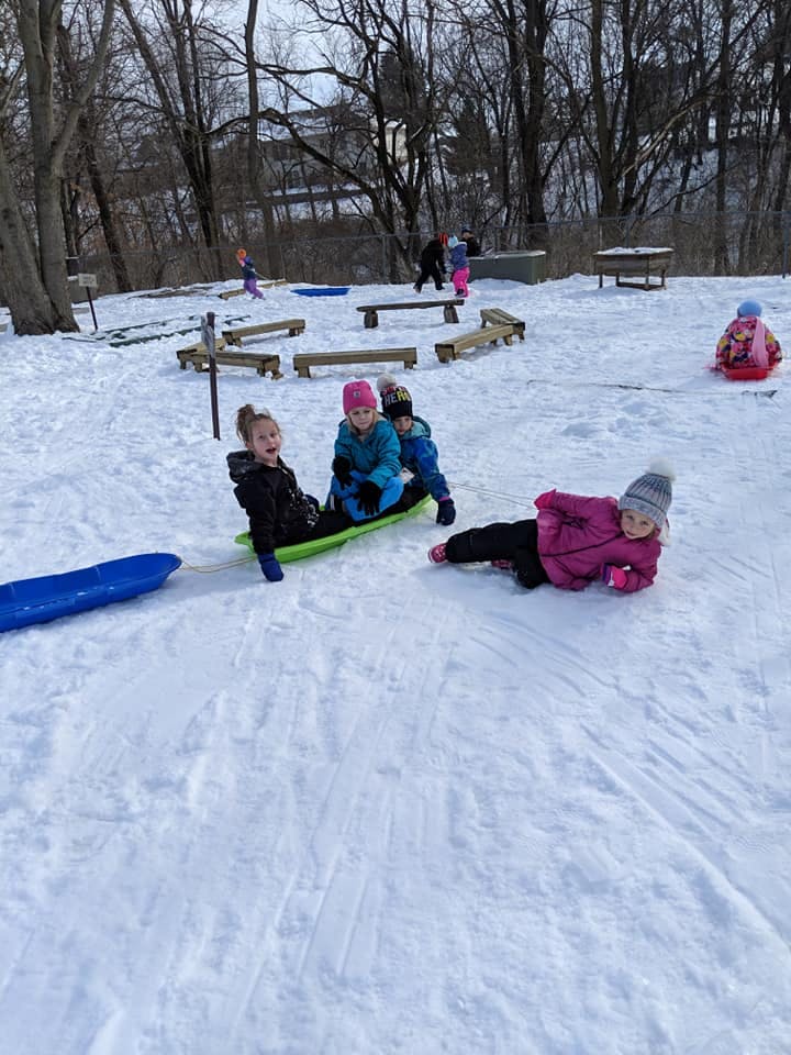 Children playing in the snow with sleds
