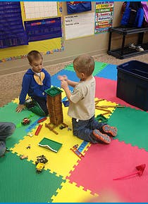 Two children playing with blocks on a colorful mat