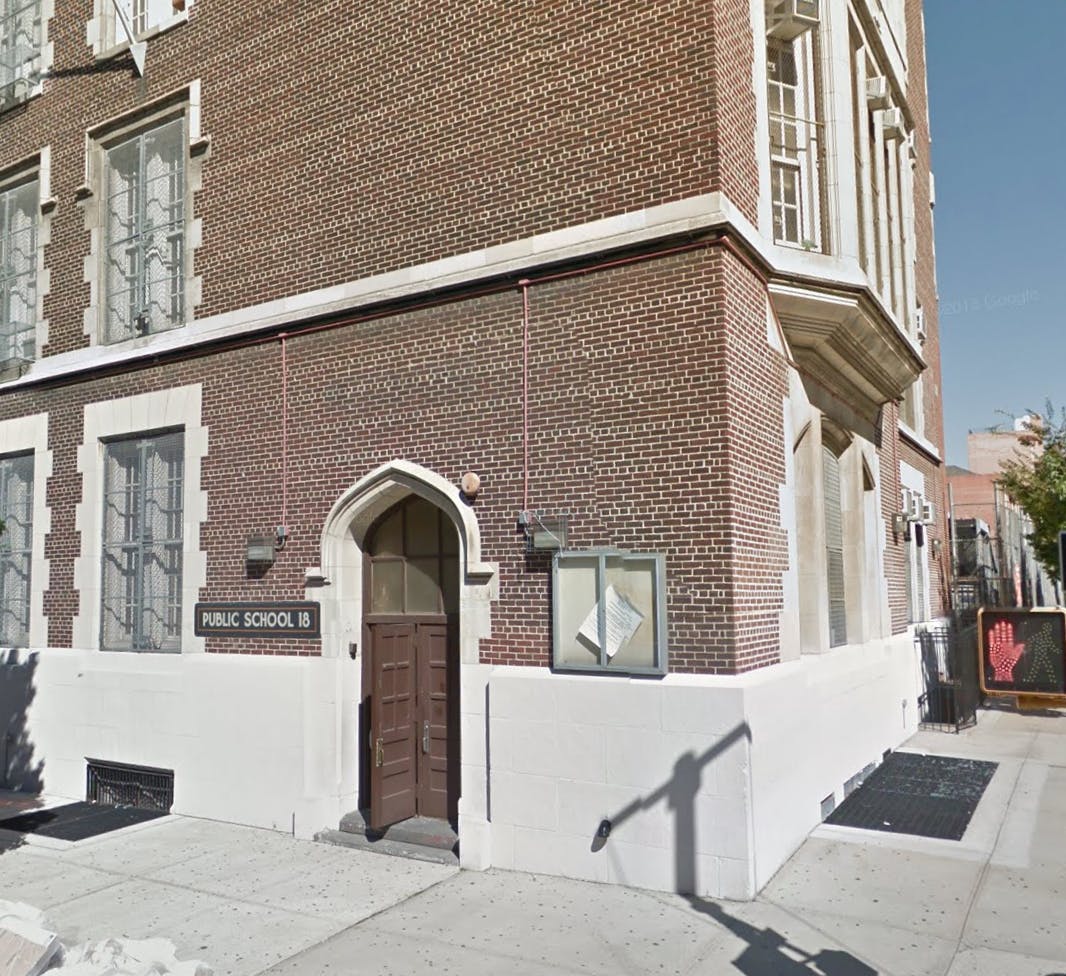 Corner of a brick building with an arched doorway and sign reading "PUBLIC SCHOOL"
