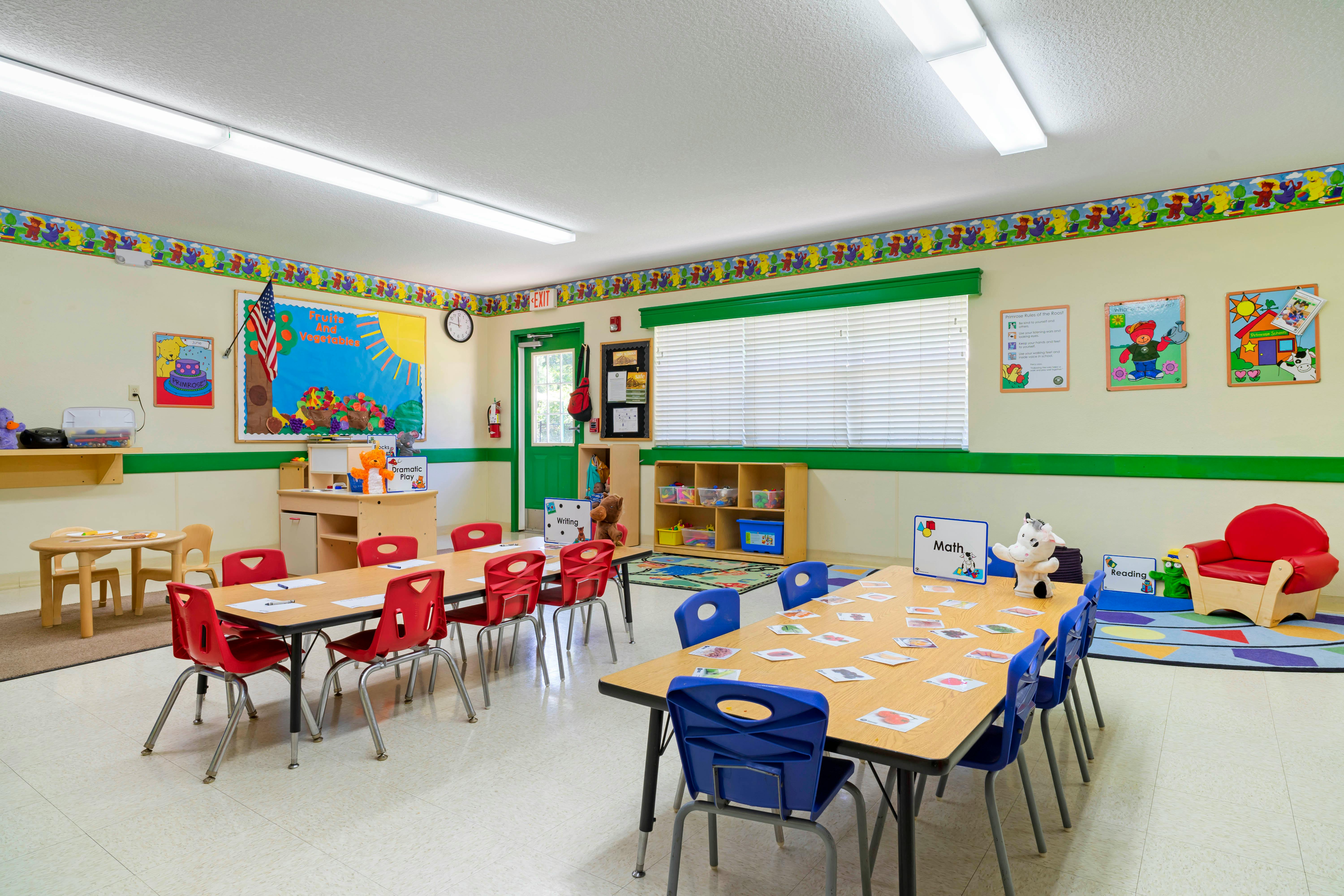 Classroom with child-sized tables and chairs, shelves, and colorful wall decorations