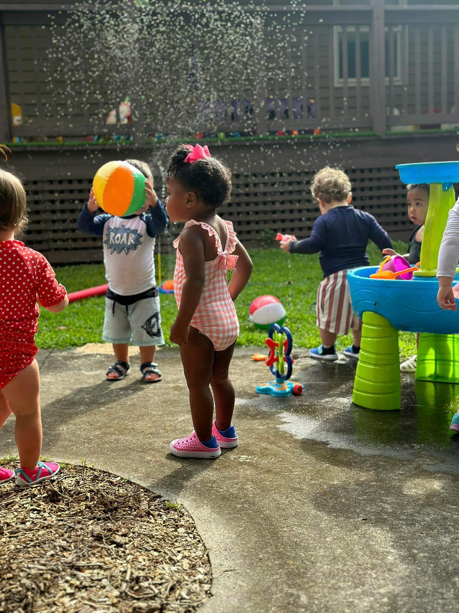 Children playing with water and a beach ball outdoors