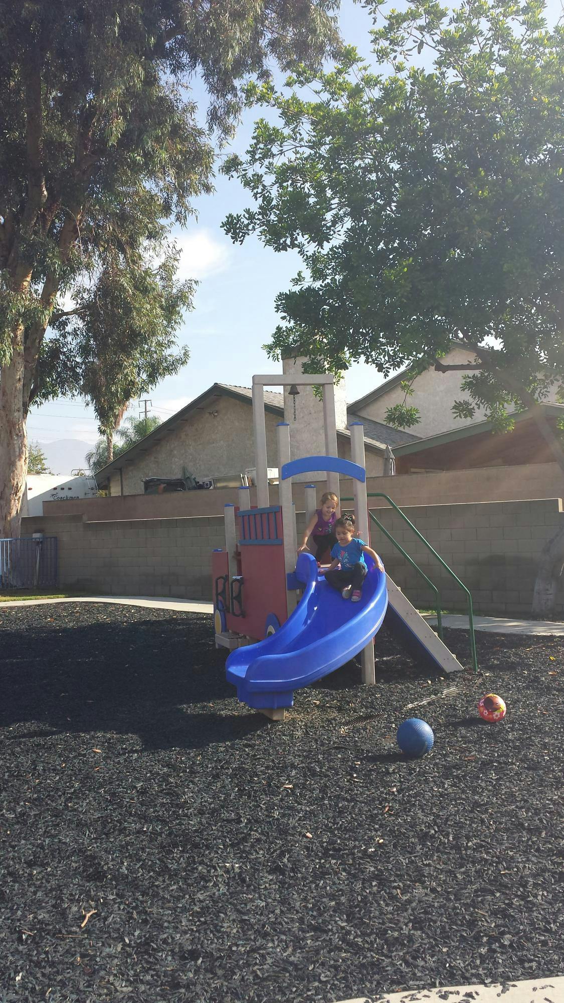 Two children on a blue slide at a playground
