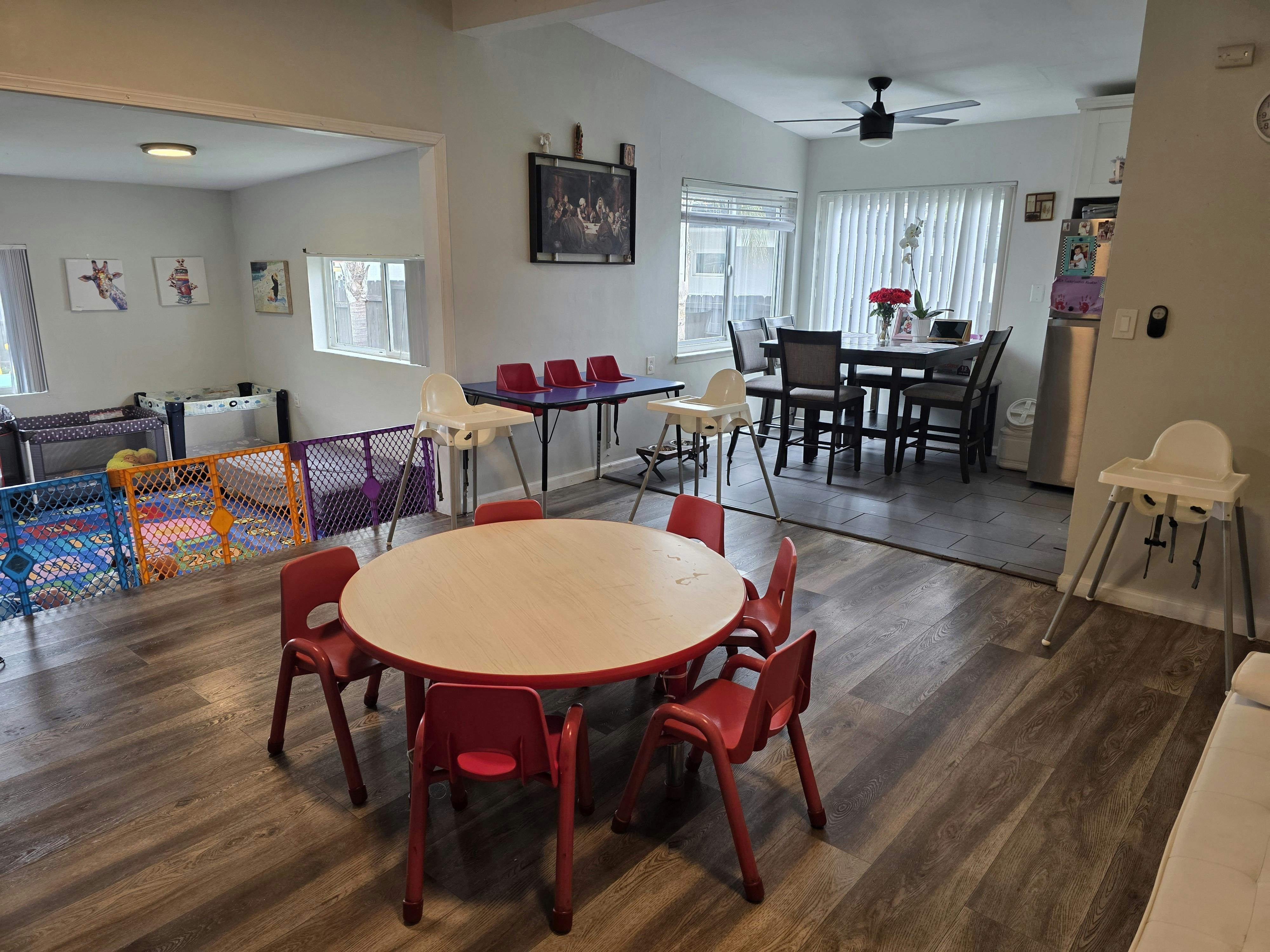Playroom with small red chairs around a round table and a playpen