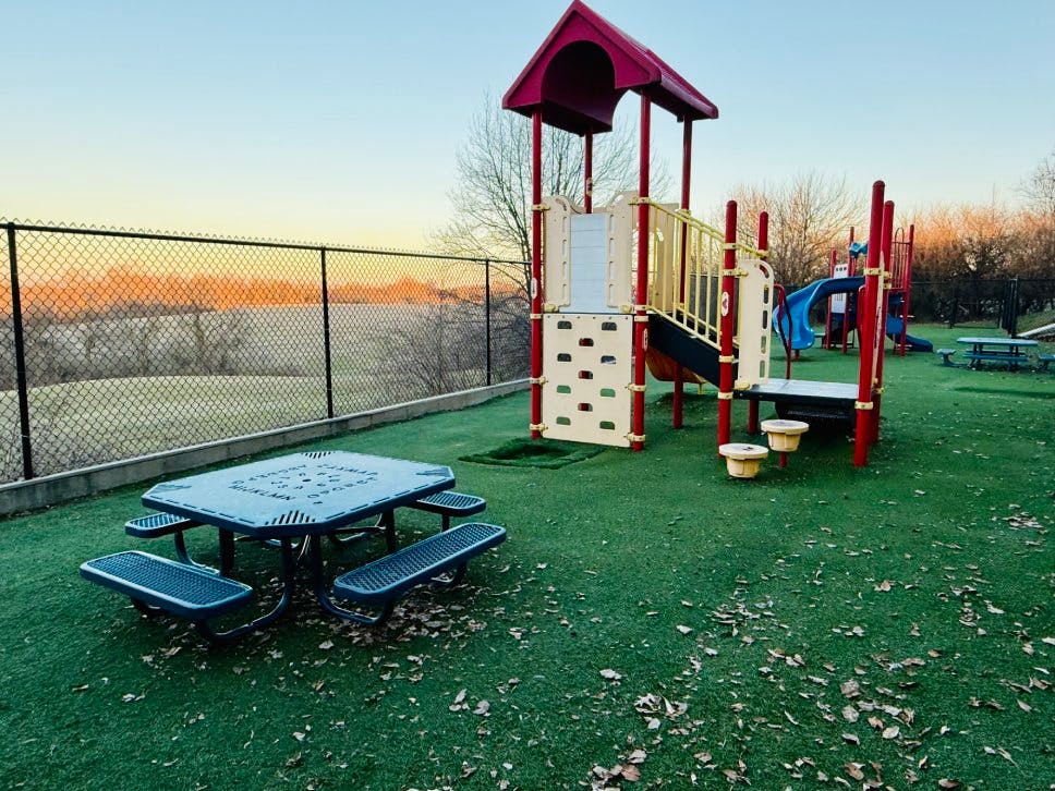 Playground with climbing structures, slides, and picnic tables on artificial turf