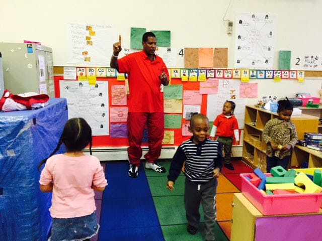 Adult person speaking to children in a classroom