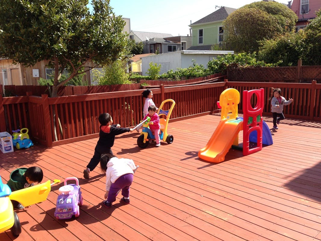 Children playing with toys and a slide on a wooden deck