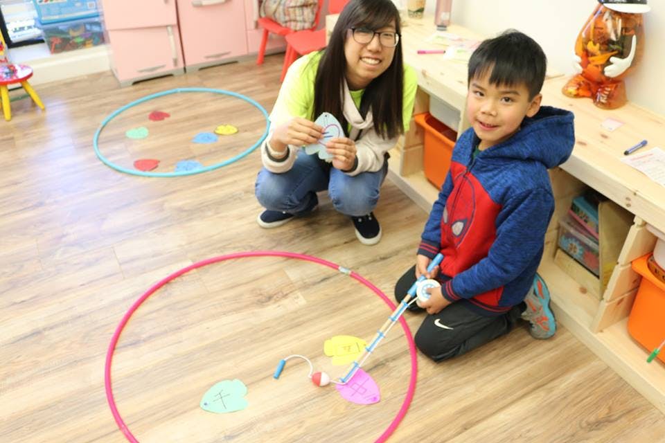 Adult and child playing a game with hoops and cutouts on the floor