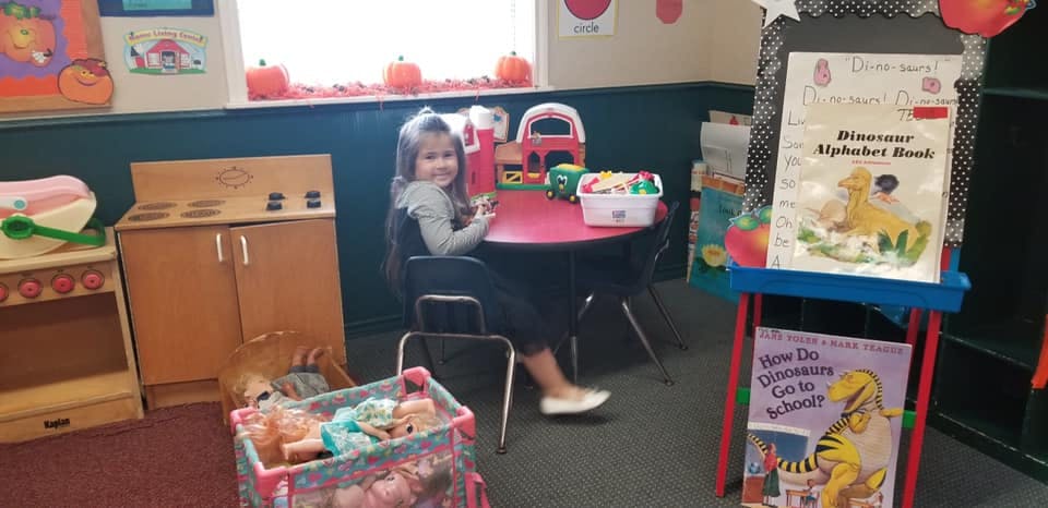 Child sitting at a small table in a classroom