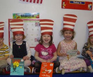 Four children wearing striped hats and holding books