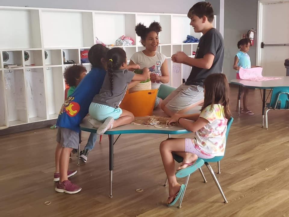 Children and teens gathered around a table, engaged in an activity