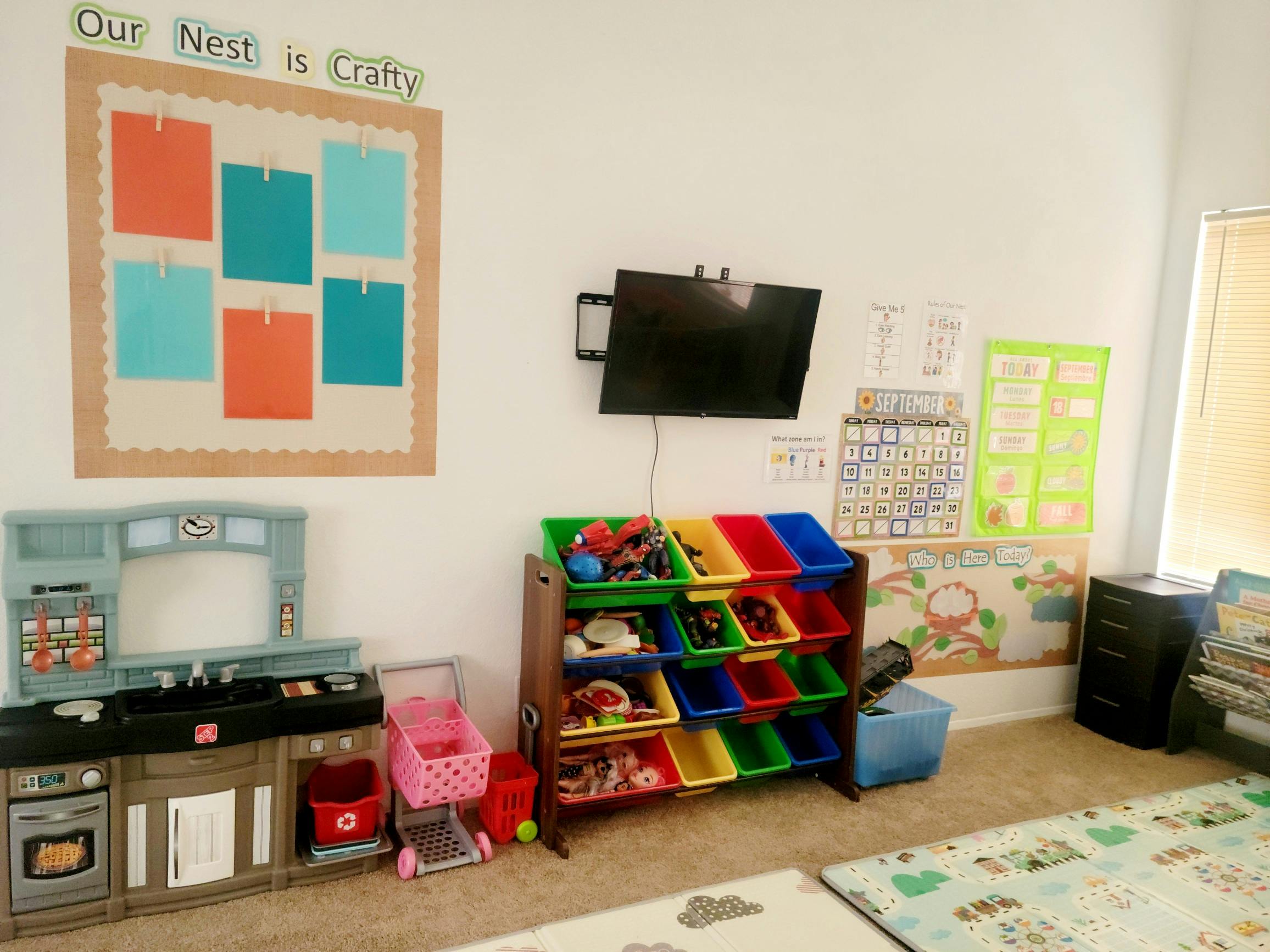 Playroom with toy kitchen, storage bins, and bulletin board