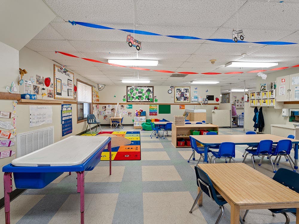 Empty classroom with small tables and chairs, colorful decorations