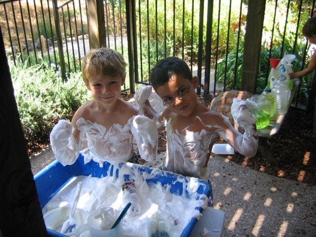 Two children playing in a tub of foam