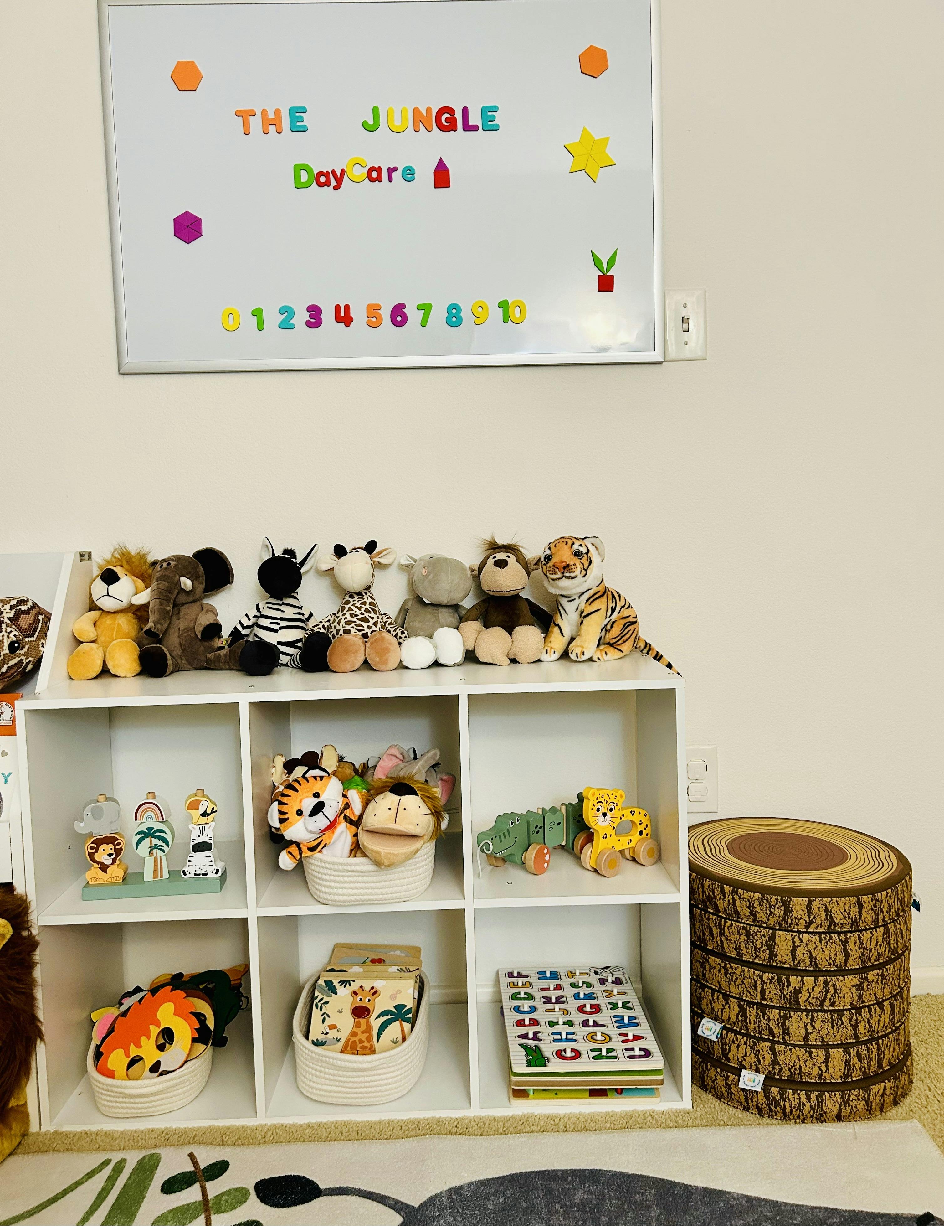 Whiteboard with "The Jungle Day Care" and numbers above a shelf with toys