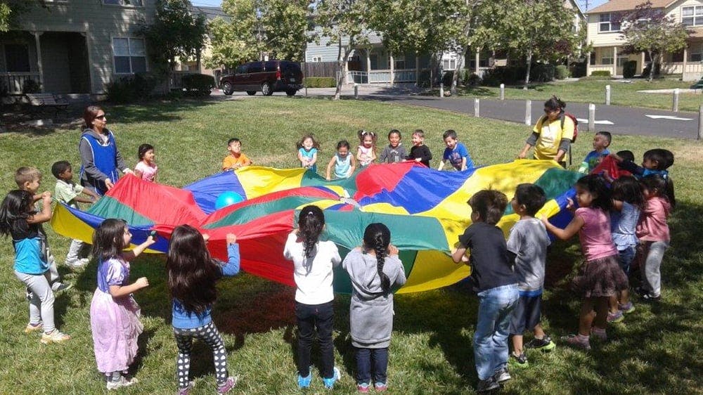 People and children playing with a colorful parachute outdoors