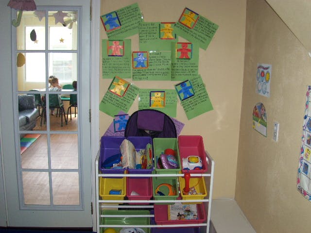 Storage unit with colorful bins next to a door, child visible through door