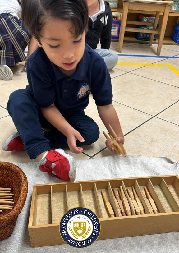 Child placing wooden spindles into a numbered Montessori box