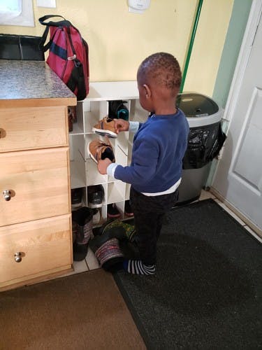 Child putting shoes into a shoe rack
