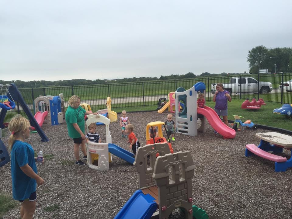 Children and adults playing on a playground with slides and swings
