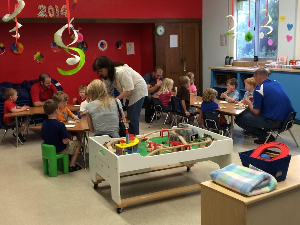 Adults and children seated at tables in a classroom
