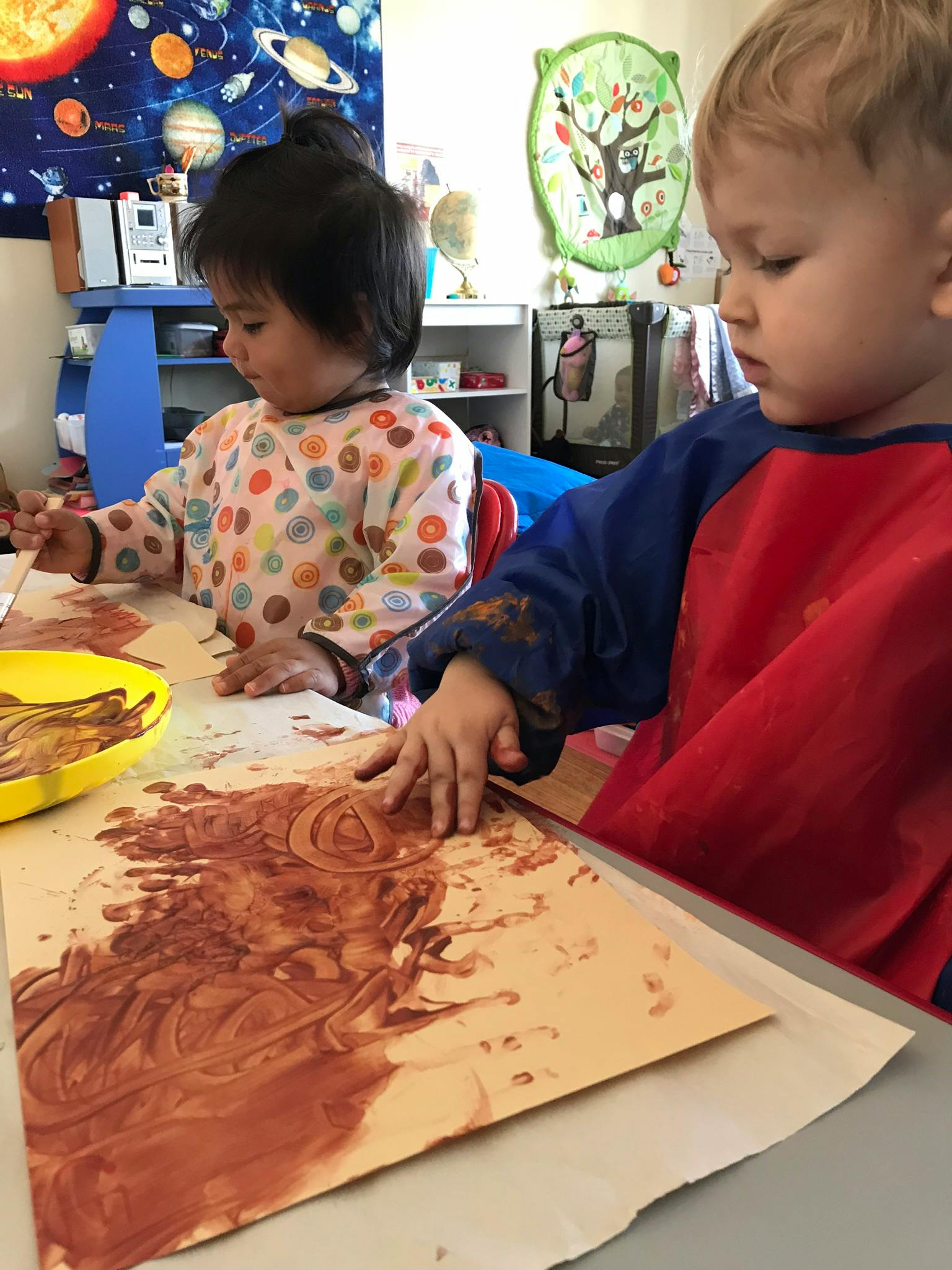 Two children finger painting at a table
