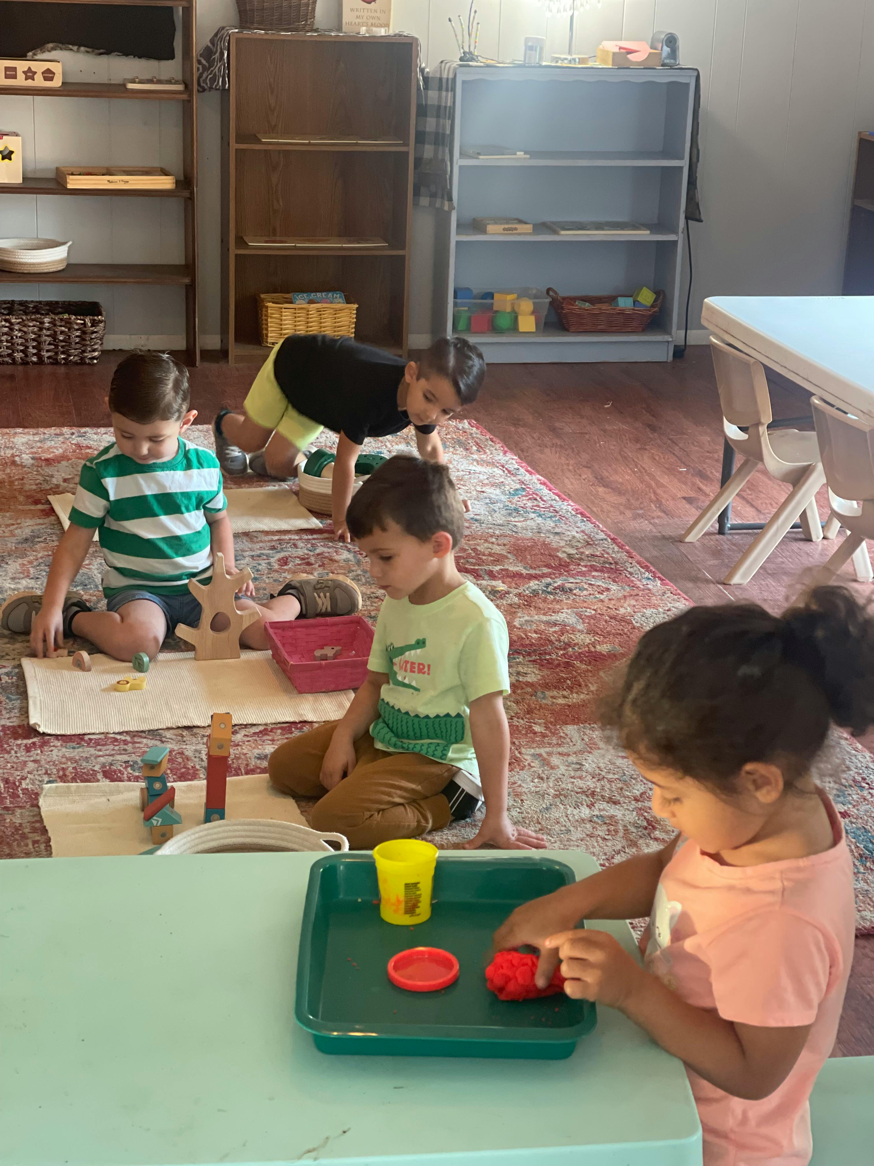 Children playing with toys on a rug and at a table