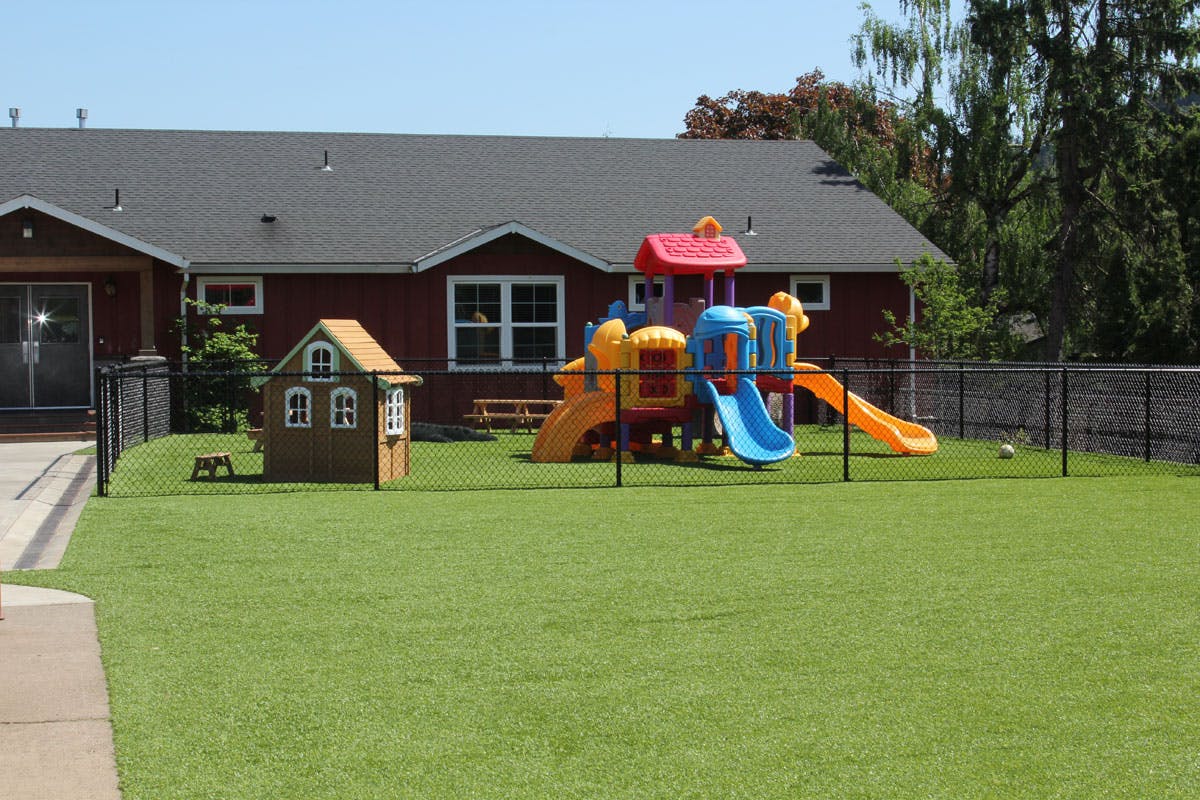 Playground with a playhouse and colorful slide structure on artificial turf