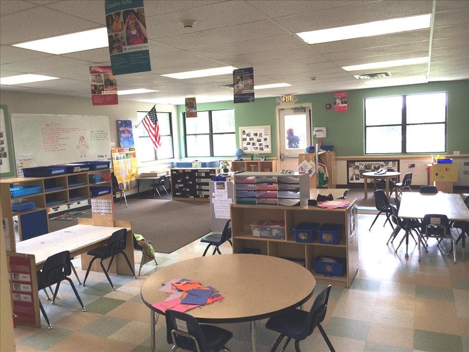 An empty kindergarten classroom with tables, chairs, and learning materials