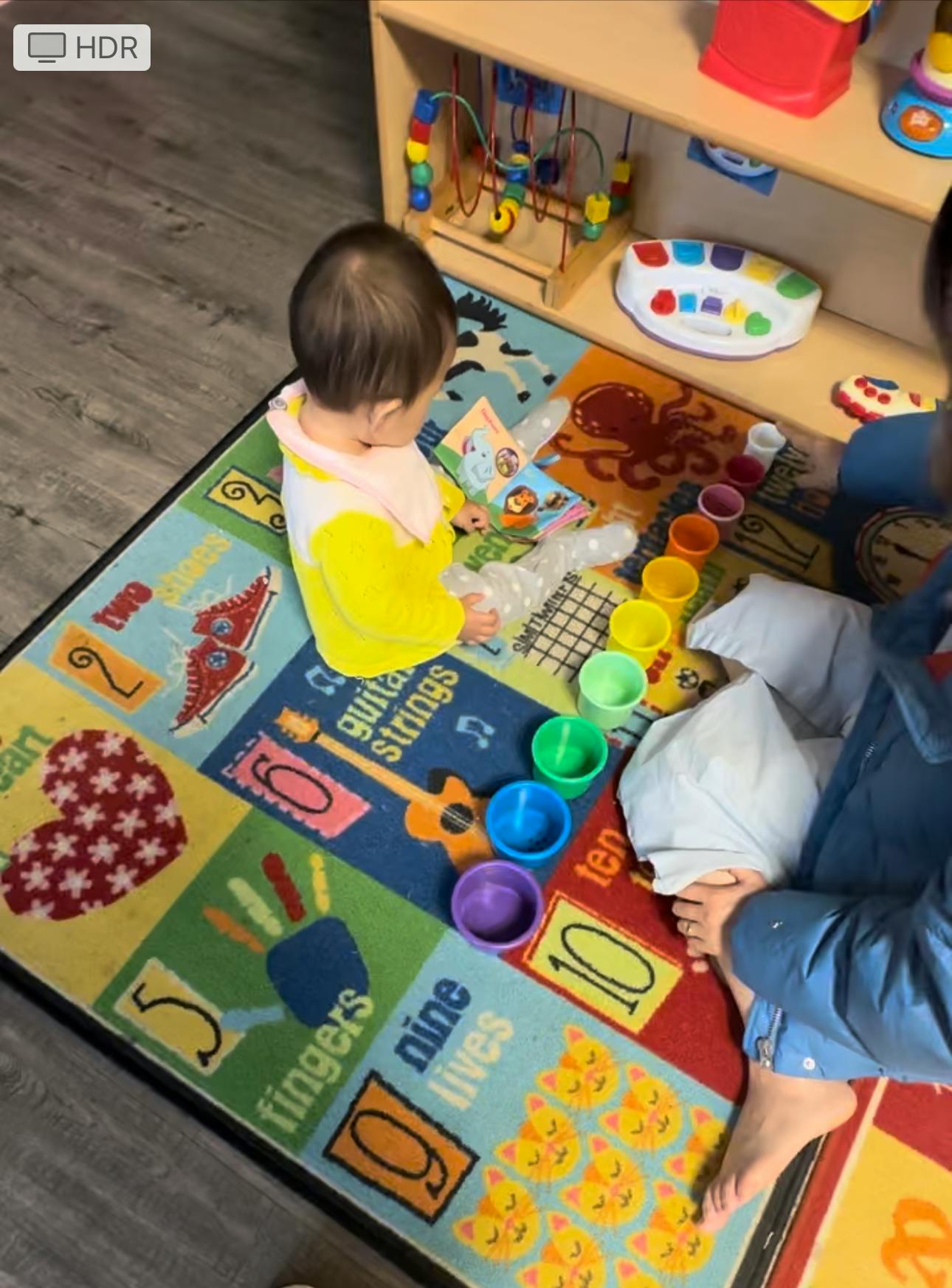Child sitting on a colorful rug with toys