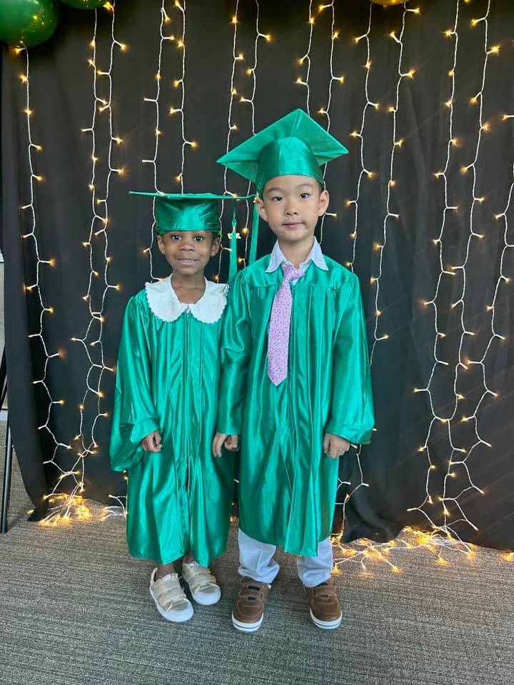 Two children in green graduation caps and gowns