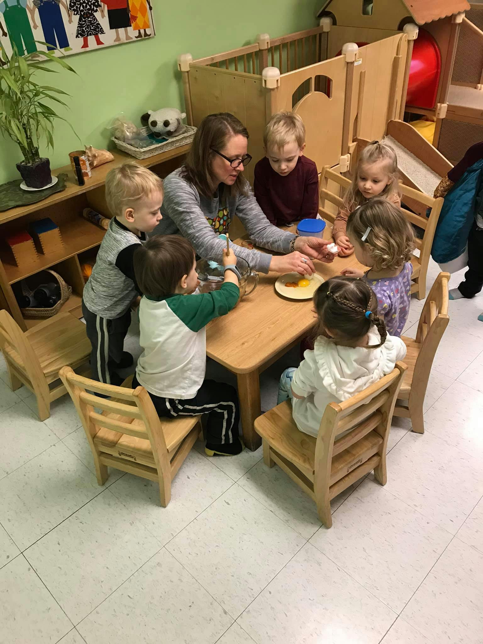 Adult and children gathered around a table in a classroom