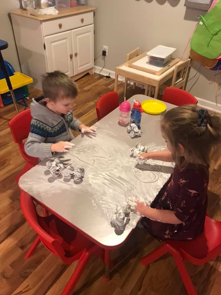 Two children playing with shaving cream on a table