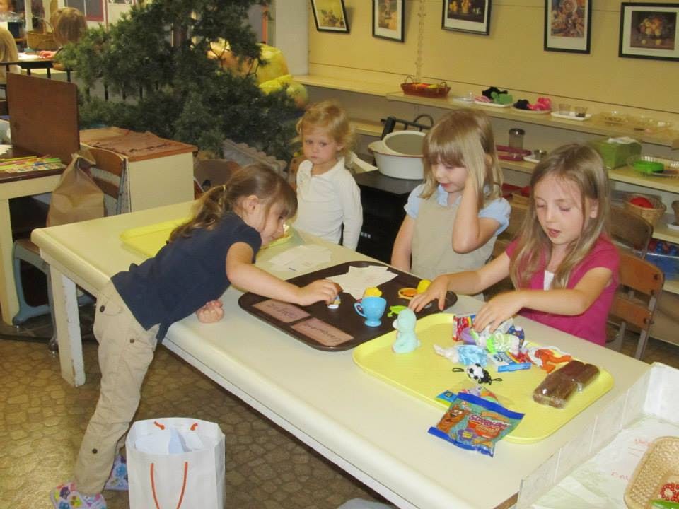 Four children playing with toys at a table in a classroom