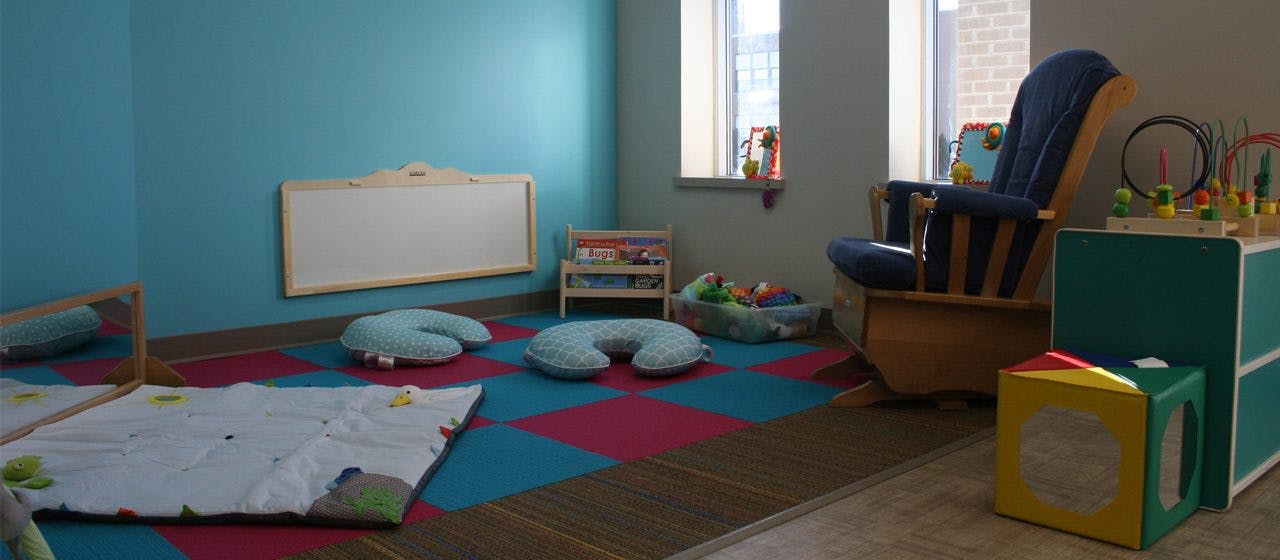 Playroom with blue and pink floor tiles, a rocking chair, and toys