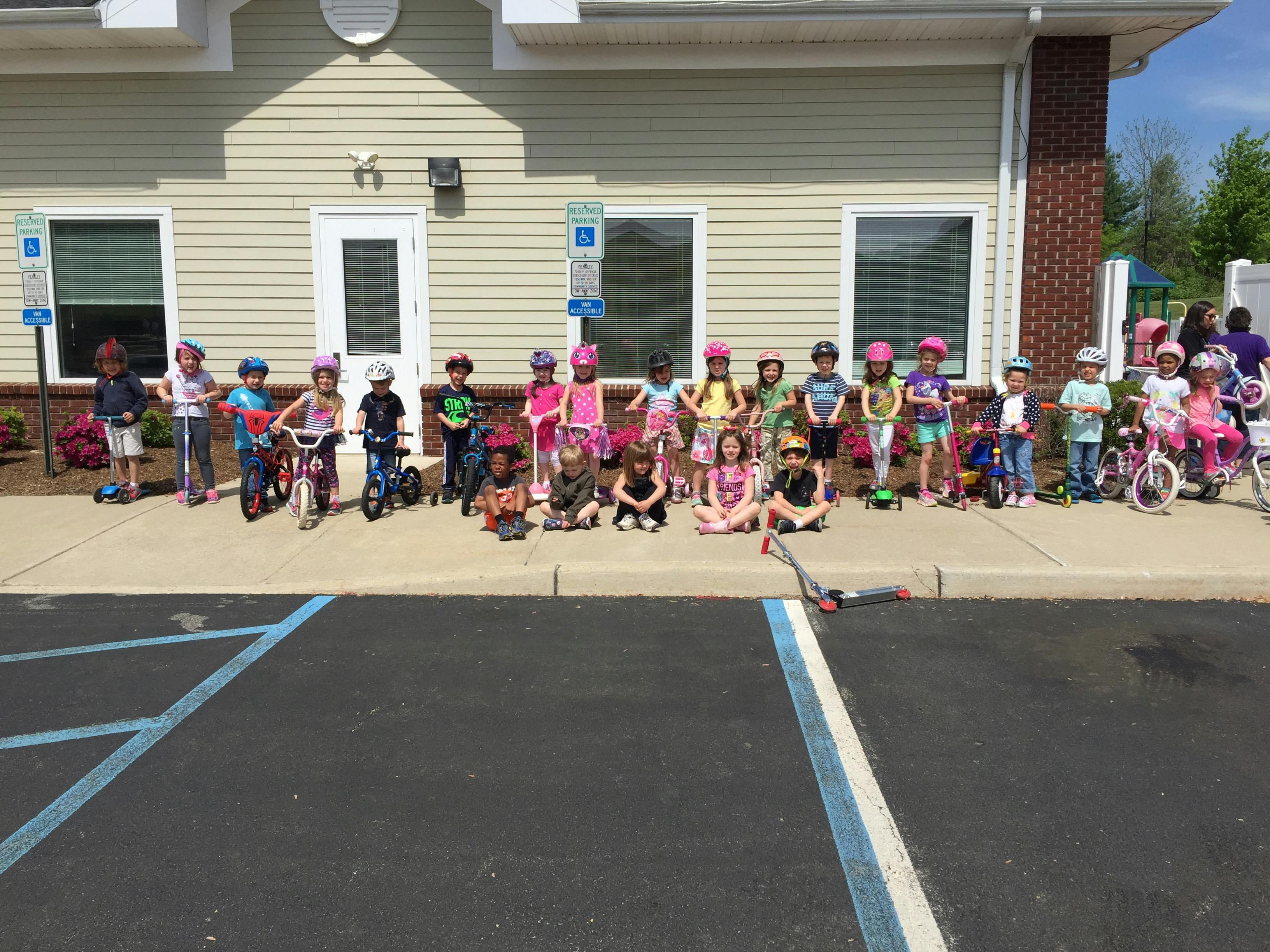 Group of children with bikes and scooters in front of a building