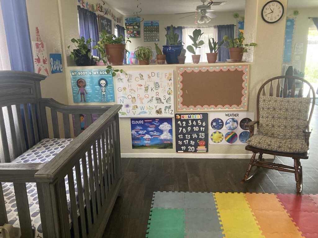 crib next to a wooden rocking chair and learning posters