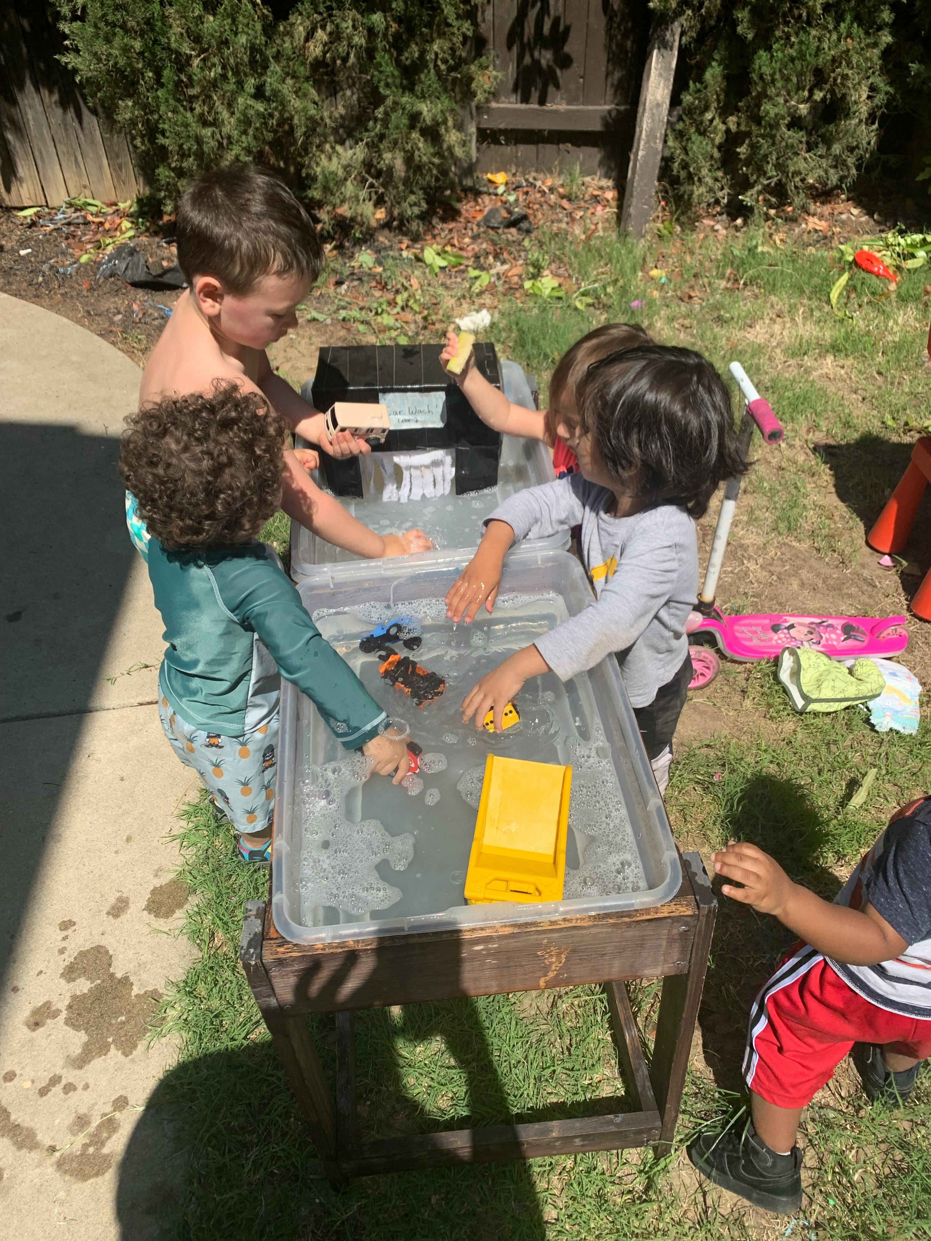 Children playing with water and toys in an outdoor water table