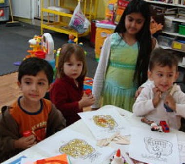 Four children at a table with drawings