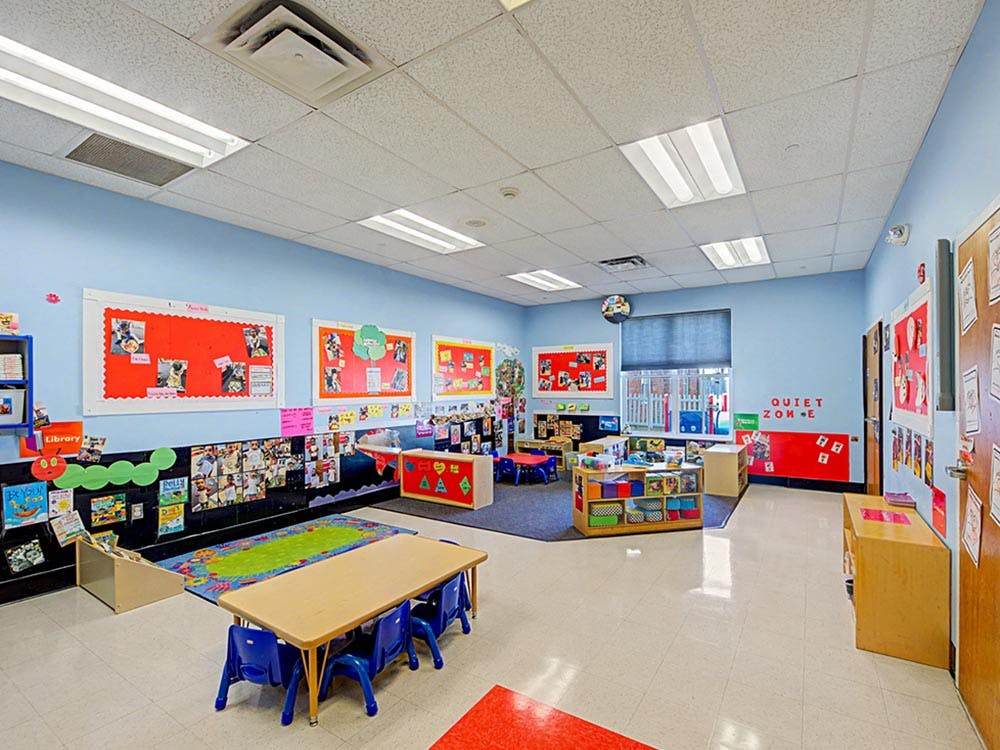 Colorful classroom with child-sized tables and chairs, bulletin boards, and bookshelves