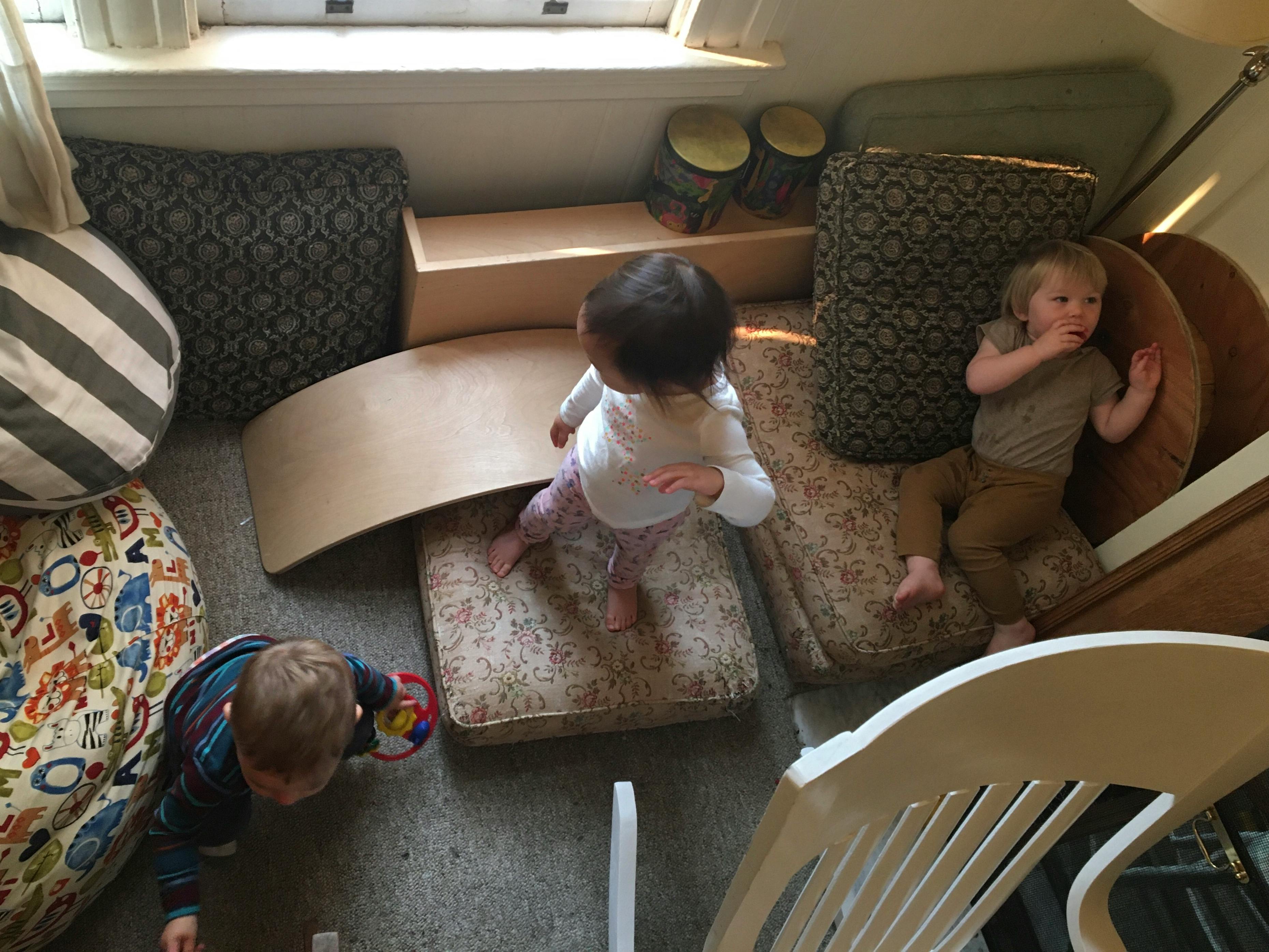 Three children playing on cushions and a wooden arch
