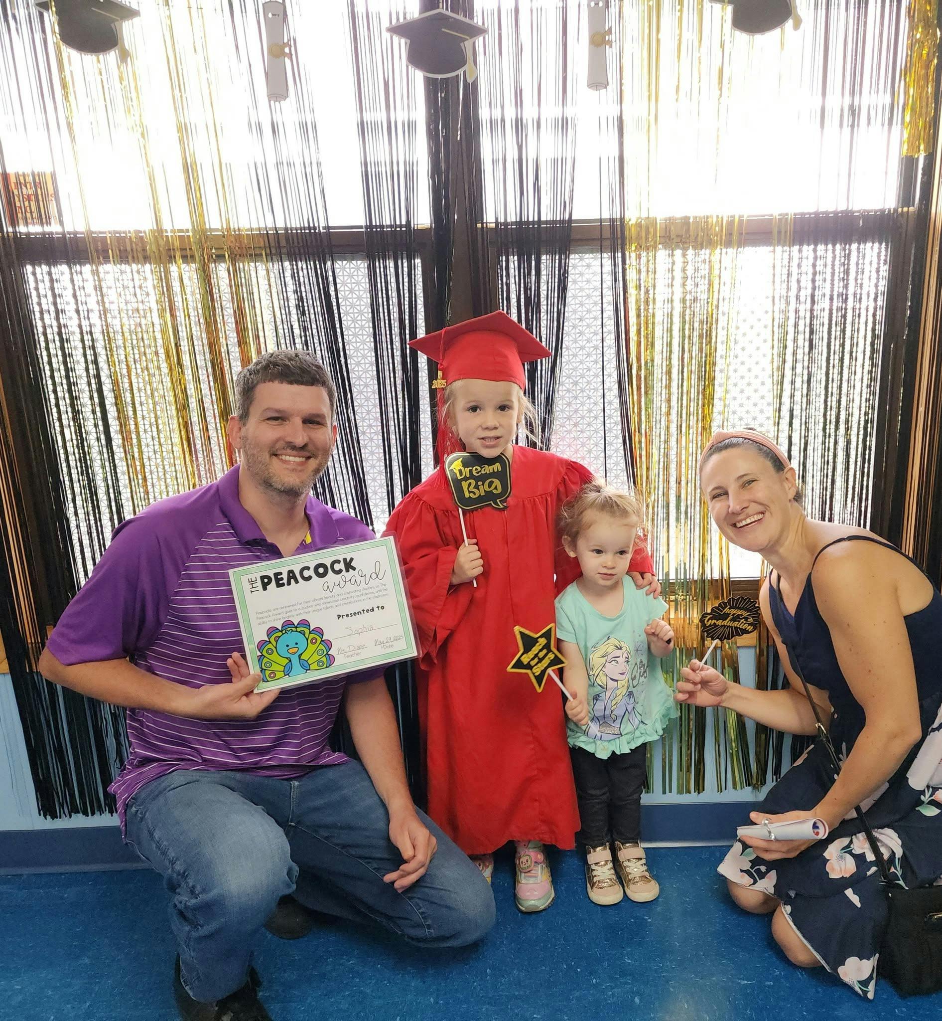 Family posing with a child in a graduation cap and gown holding a prop