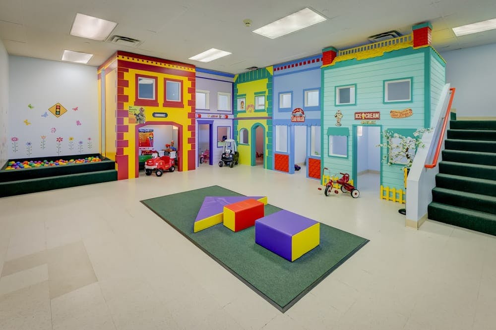 Indoor play area with colorful building facades, a ball pit, and soft play blocks