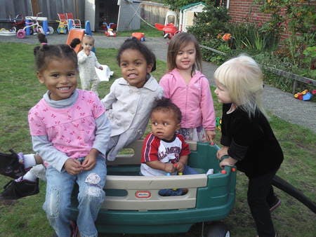 Group of children playing with a toy wagon outdoors
