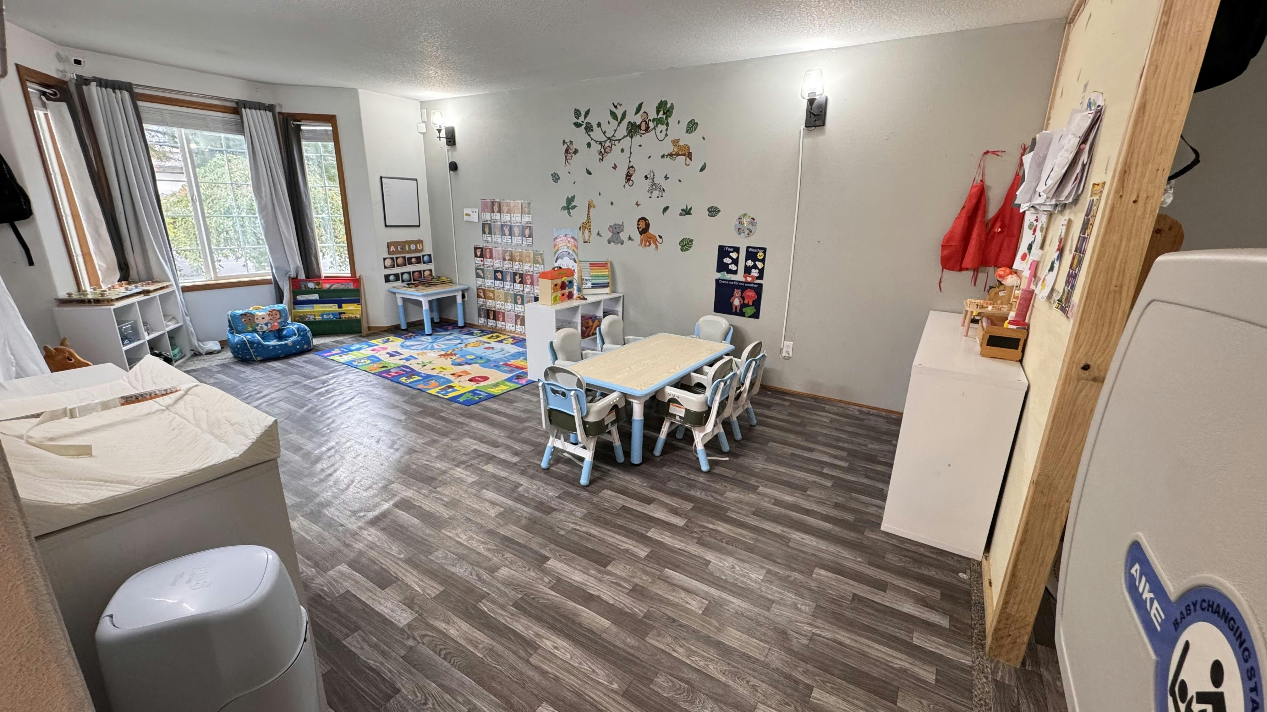 Playroom with small tables and chairs, colorful rug, and wall decorations
