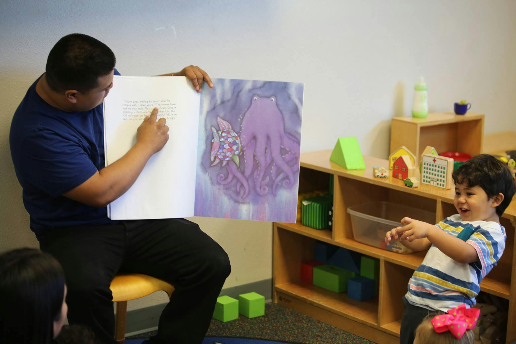 Person reading a book to a child in a classroom