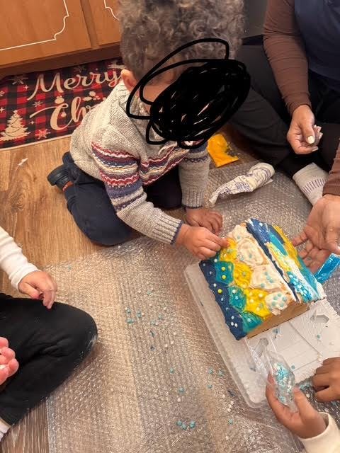 Child decorating a gingerbread house with sprinkles