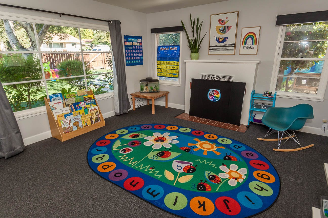 Classroom with colorful alphabet rug, book display, and windows