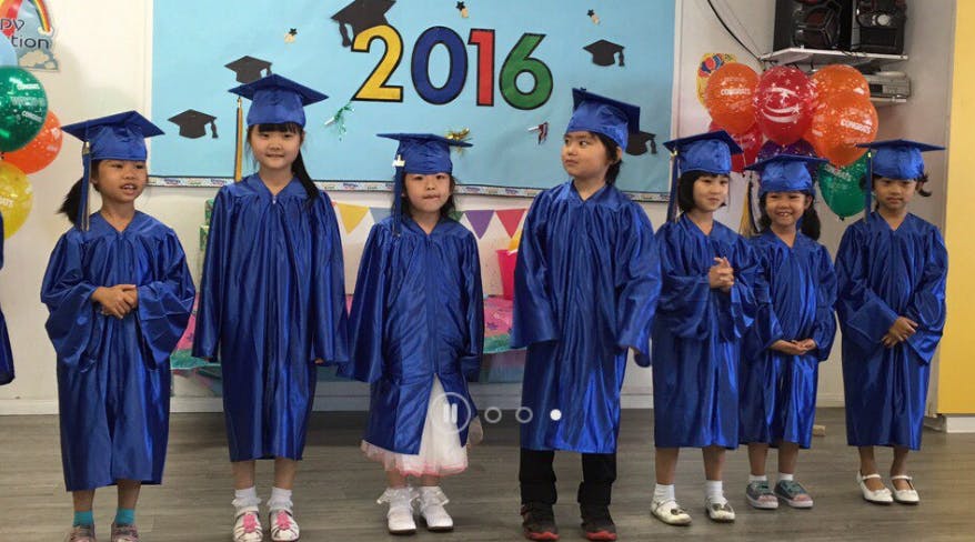 Children in blue graduation caps and gowns standing in a line